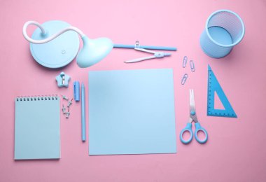 Pembe pastel arka planda mavi kırtasiye seti. Okula, eğitime, ofis malzemelerine. Düz yatıyordu. Üst Manzara. Yaratıcı yerleşim