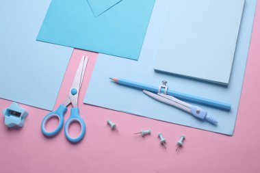 Pembe pastel arka planda mavi kırtasiye seti. Okula, eğitime, ofis malzemelerine. Düz yatıyordu. Üst Manzara. Yaratıcı yerleşim