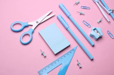 Pembe pastel arka planda mavi kırtasiye seti. Okula, eğitime, ofis malzemelerine. Düz yatıyordu. Üst Manzara. Yaratıcı yerleşim
