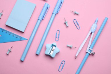 Pembe pastel arka planda mavi kırtasiye seti. Okula, eğitime, ofis malzemelerine. Düz yatıyordu. Üst Manzara. Yaratıcı yerleşim