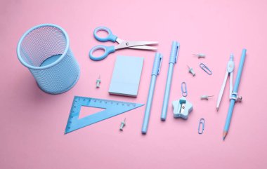 Pembe pastel arka planda mavi kırtasiye seti. Okula, eğitime, ofis malzemelerine. Düz yatıyordu. Üst Manzara. Yaratıcı yerleşim