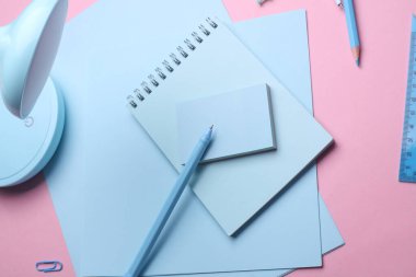 Pembe pastel arka planda mavi kırtasiye seti. Okula, eğitime, ofis malzemelerine. Düz yatıyordu. Üst Manzara. Yaratıcı yerleşim