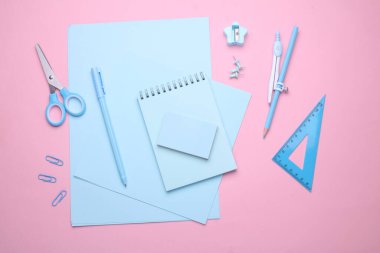 Pembe pastel arka planda mavi kırtasiye seti. Okula, eğitime, ofis malzemelerine. Düz yatıyordu. Üst Manzara. Yaratıcı yerleşim