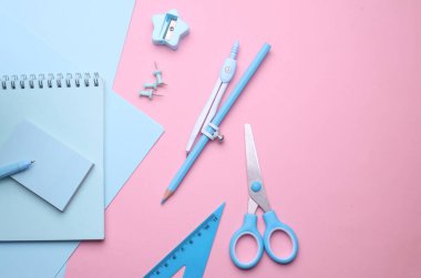 Pembe pastel arka planda mavi kırtasiye seti. Okula, eğitime, ofis malzemelerine. Düz yatıyordu. Üst Manzara. Yaratıcı yerleşim