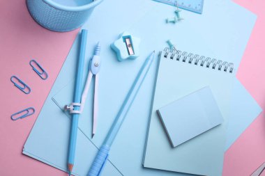 Pembe pastel arka planda mavi kırtasiye seti. Okula, eğitime, ofis malzemelerine. Düz yatıyordu. Üst Manzara. Yaratıcı yerleşim