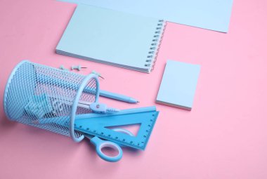 Pembe pastel arka planda mavi kırtasiye seti. Okula, eğitime, ofis malzemelerine. Düz yatıyordu. Üst Manzara. Yaratıcı yerleşim
