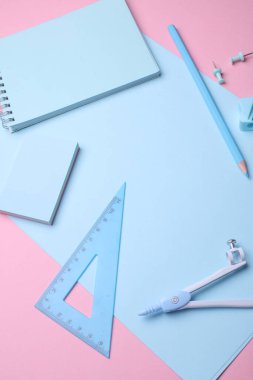 Pembe pastel arka planda mavi kırtasiye seti. Okula, eğitime, ofis malzemelerine. Düz yatıyordu. Üst Manzara. Yaratıcı yerleşim