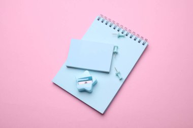 Pembe arka planda kırtasiyeli mavi defter. Üst görünüm