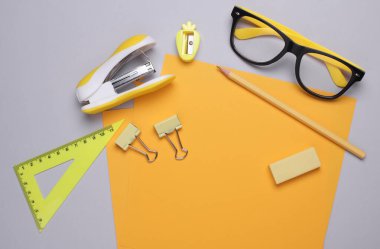 Gözlüklü sarı kağıtlar ve gri arka planda kırtasiye.