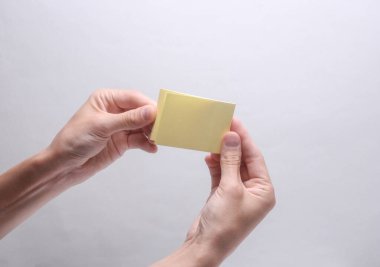 Gri arkaplanda not kâğıdı çıkartması tutan kadın eller