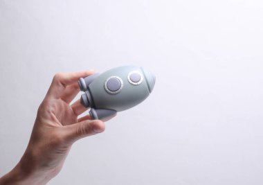 Gri arka planda oyuncak bir uzay mekiği modeli tutan bir kadın. Açılış