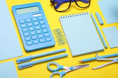 Sarı arka planda mavi kırtasiye seti. Okula, eğitime, ofis malzemelerine. Düz yatıyordu. Üst Manzara. Yaratıcı yerleşim