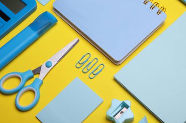 Sarı arka planda mavi kırtasiye seti. Okula, eğitime, ofis malzemelerine. Düz yatıyordu. Üst Manzara. Yaratıcı yerleşim