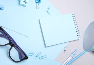 Mavi kırtasiye seti ve gri arka planda kağıt kağıtlar. Okula, eğitime, ofis malzemelerine. Düz yatıyordu. Üst Manzara. Yaratıcı yerleşim