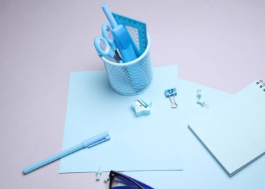 Mavi kırtasiye seti ve gri arka planda kağıt kağıtlar. Okula, eğitime, ofis malzemelerine. Düz yatıyordu. Üst Manzara. Yaratıcı yerleşim