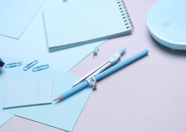 Mavi kırtasiye seti ve gri arka planda kağıt kağıtlar. Okula, eğitime, ofis malzemelerine. Düz yatıyordu. Üst Manzara. Yaratıcı yerleşim