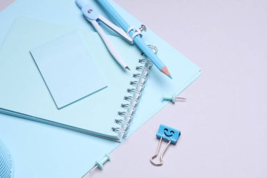 Mavi kırtasiye seti ve gri arka planda kağıt kağıtlar. Okula, eğitime, ofis malzemelerine. Düz yatıyordu. Üst Manzara. Yaratıcı yerleşim