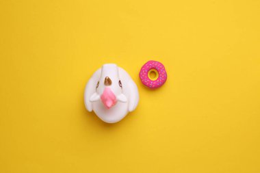 Sarı arka planda donutlu lastik banyo tek boynuzlu atı. Üst görünüm.