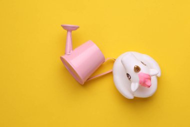 Sarı arka planda su tenekesi olan lastik tek boynuzlu at.