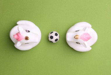 Yeşil arka planda futbol topu olan lastik küvetli tek boynuzlu atlar. Üst Manzara. Spor konsepti