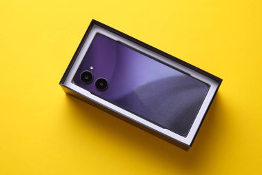 Sarı arka plandaki bir kutuda yeni modern akıllı telefon