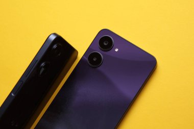 Çift kameralı iki modern akıllı telefon, arka kapaktan görüntü. Sarı arkaplan