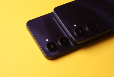 Çift kameralı iki modern akıllı telefon, arka kapaktan görüntü. Sarı arkaplan