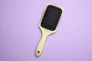 Saç fırçası, mor arkaplanda plastik tarak