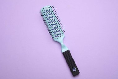 Saç fırçası, mor arkaplanda plastik tarak