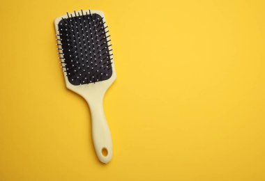 Saç fırçası, sarı arkaplanda plastik tarak