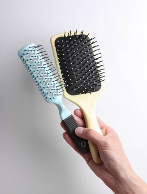 Gri arkaplanda saç fırçası tutan kadın.