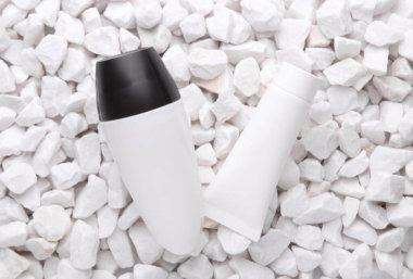 Beyaz terleme önleyici çubuk ve çakıl taşlı krema tüpü.