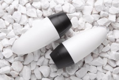 Beyaz terleme önleyici çubuk tüpleri çakıl taşlarına yakın.