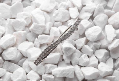 Beyaz çakıl taşlarının üzerine takı iğnesi yakın.