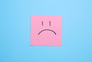 Kare not kağıdındaki mutsuz surat, mavi arkaplan. İş konsepti