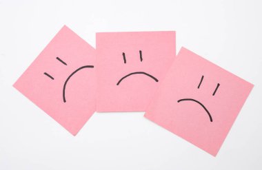 Kare kağıtlarda mutsuz yüzler, beyaz arka plan. İş konsepti