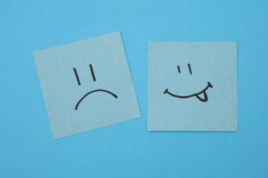 Kare kağıtlarda mutlu ve mutsuz yüzler, mavi arka plan. İş konsepti
