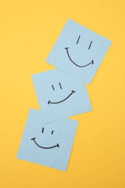 Kare notlarda mutlu yüzler, sarı arka plan. İş konsepti