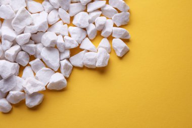 Sarı zemin üzerinde beyaz çakıl taşları.