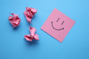 Kare kağıtta gülen surat, mavi arka plan. İş konsepti