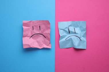 Buruşuk karton kağıtlarda mutsuz yüzler, mavi pembe arka plan. İş konsepti