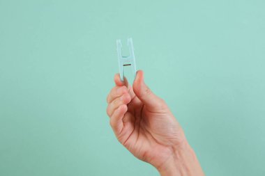 Mavi arka planda çamaşır mandalını tutan kadın.