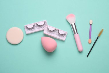 Sahte kirpikler, makyaj fırçaları, mavi arka planda süngerler. Güzellik konsepti. Düz yatıyordu