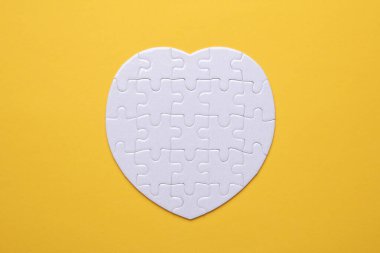 Sarı arka planda beyaz, boş kalp şeklinde bir yapboz. Tasarım için model