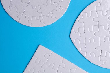 Mavi arkaplanda farklı şekillerde beyaz, boş yapboz bulmacaları