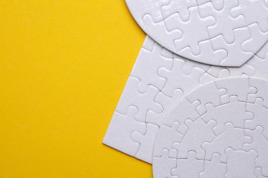 Sarı arka planda farklı şekillerde beyaz, boş yapboz bulmacaları