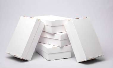 Gri zemin üzerinde beyaz karton kutular yığını