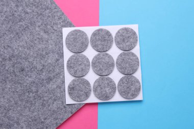 Pembe mavi arka planda mobilyalar için koruyucu daire pedleri hissettim.