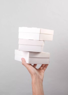 Gri arka planda beyaz karton kutular tutan kadın. Yemek teslimatı, markalaşma, maket