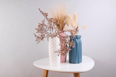 Kahve masasında kurumuş çiçekli vazolar.